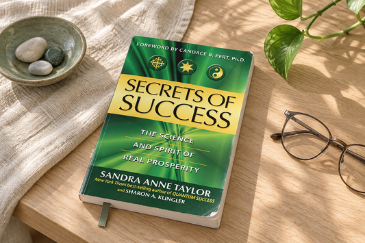 Secrets of Success lying on a natural wood table with reading glasses, linen and soft greenery